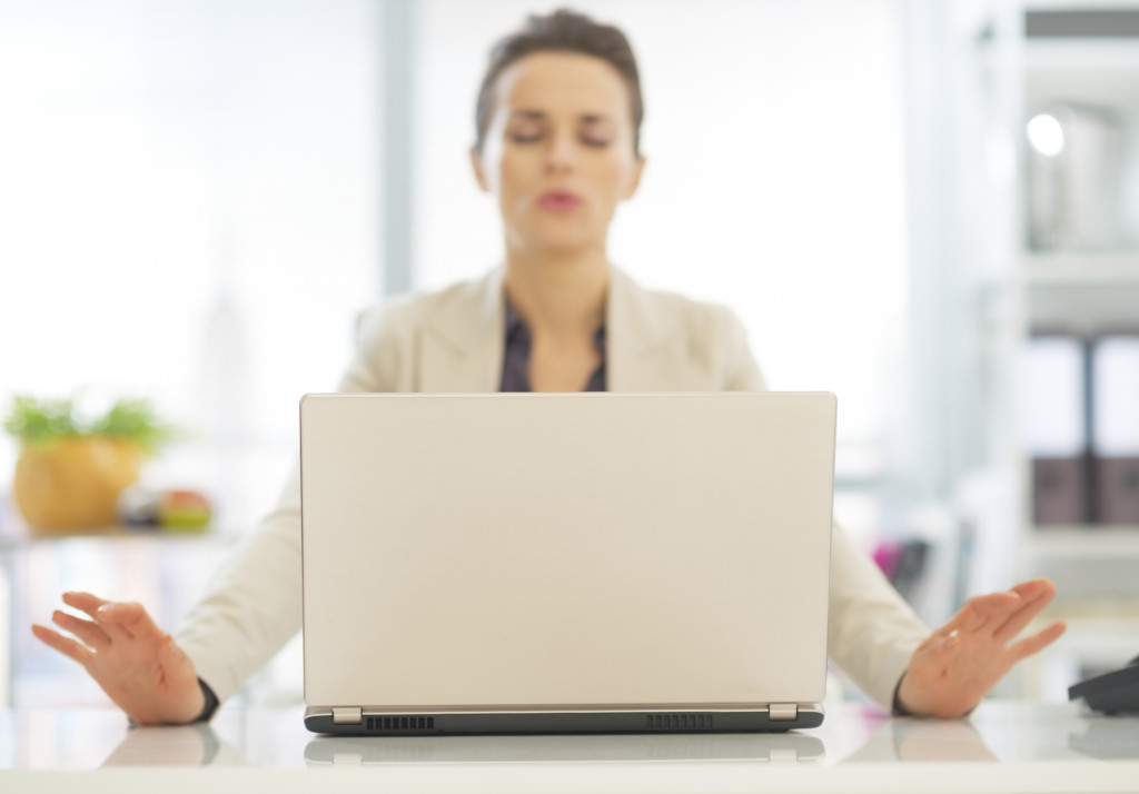 Closeup on laptop and relaxing business woman in background
